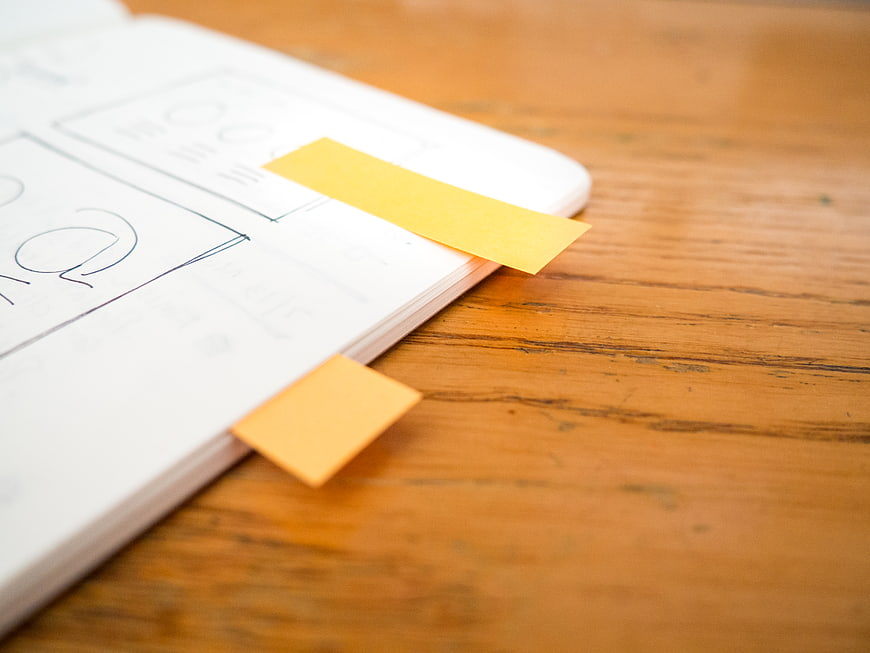 Notebook with sticky notes on wooden desk