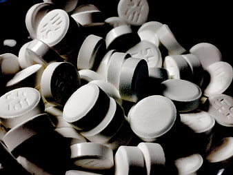 Close-up of scattered white pharmaceutical pills on black background