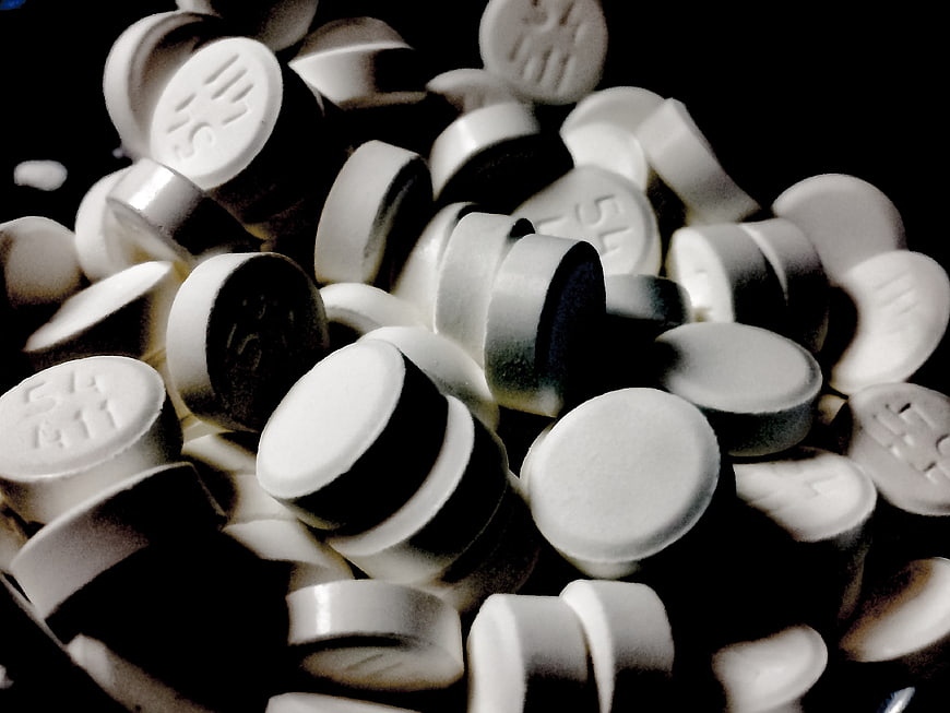 Close-up of scattered white pharmaceutical pills on black background