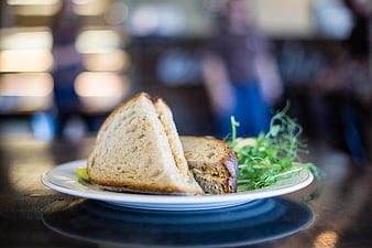 Gourmet Sandwich on White Plate with Greens in Cafe