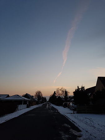 Winter suburban street with contrail at dusk