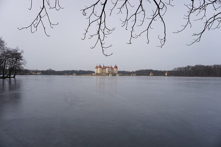 Moritzburg Castle reflected on frozen lake in winter