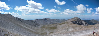 Panoramic mountain landscape with hiker and blue sky