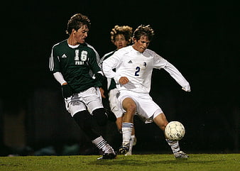 Soccer players competing for the ball at night