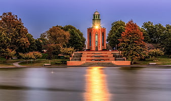 Red brick church tower with light reflection on calm water