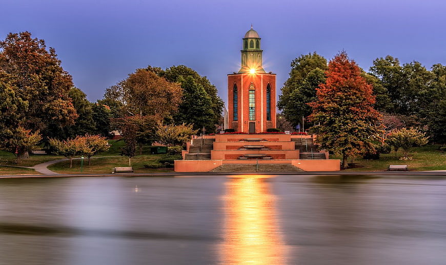 Red brick church tower with light reflection on calm water