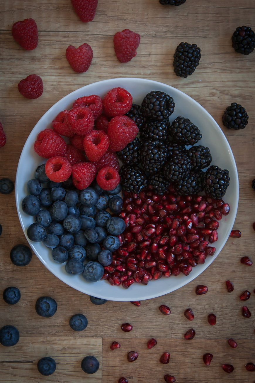 Top View of Mixed Berries and Pomegranate Seeds on Wooden Table