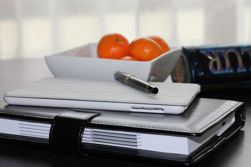 Office desk with notebook, pen, tablet, and tangerines