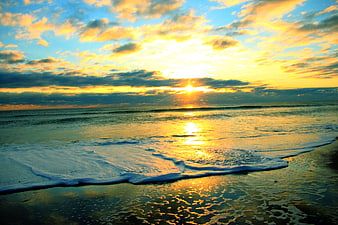 Golden Sunrise Over Ocean Waves And Sandy Beach