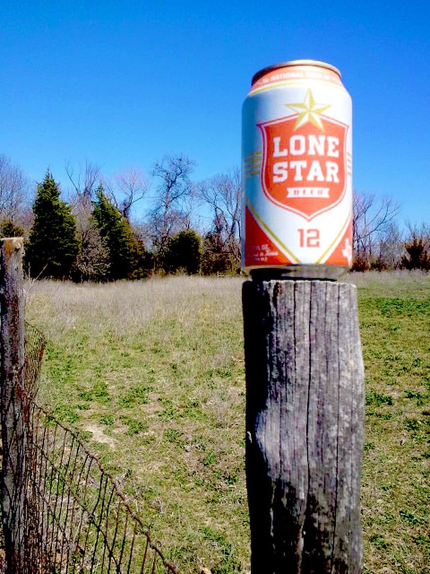 Lone Star Beer Can on Wooden Fence Post in Field