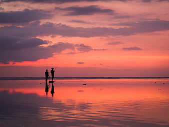 Silhouetted Fishermen on Beach at Vibrant Sunset