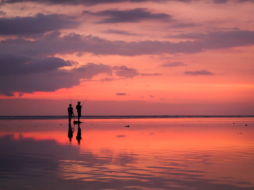 Silhouetted Fishermen on Beach at Vibrant Sunset