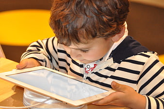 Young boy using white tablet computer indoors