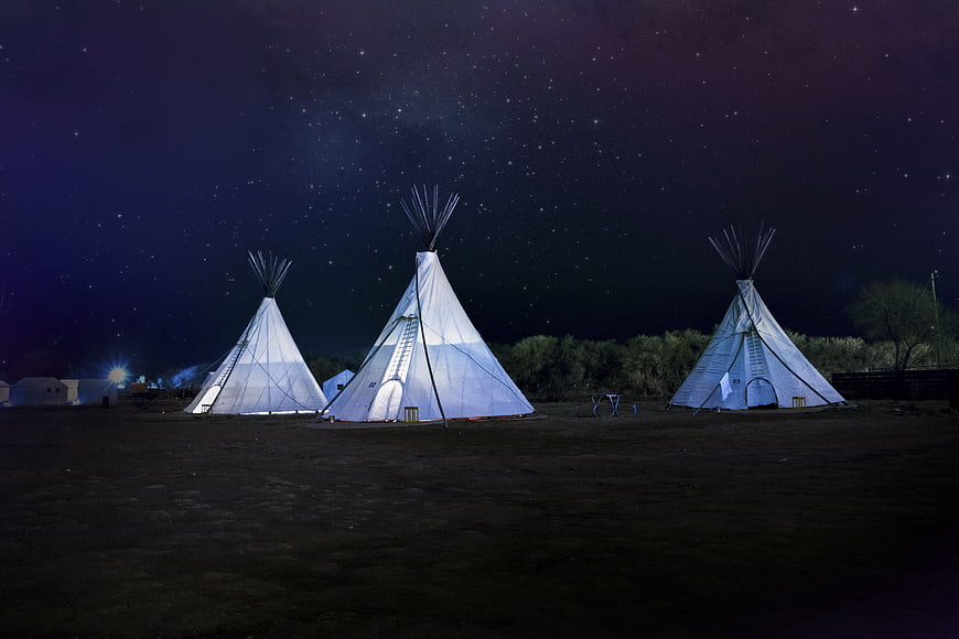 Illuminated Teepees Under Starry Night Sky