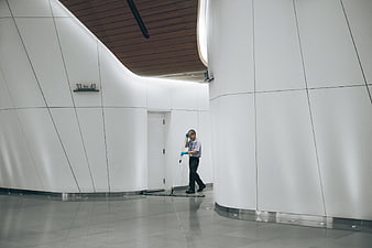 Janitor mopping floor in modern white curved hallway