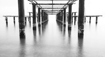 Black and white long exposure of a pier structure in calm water
