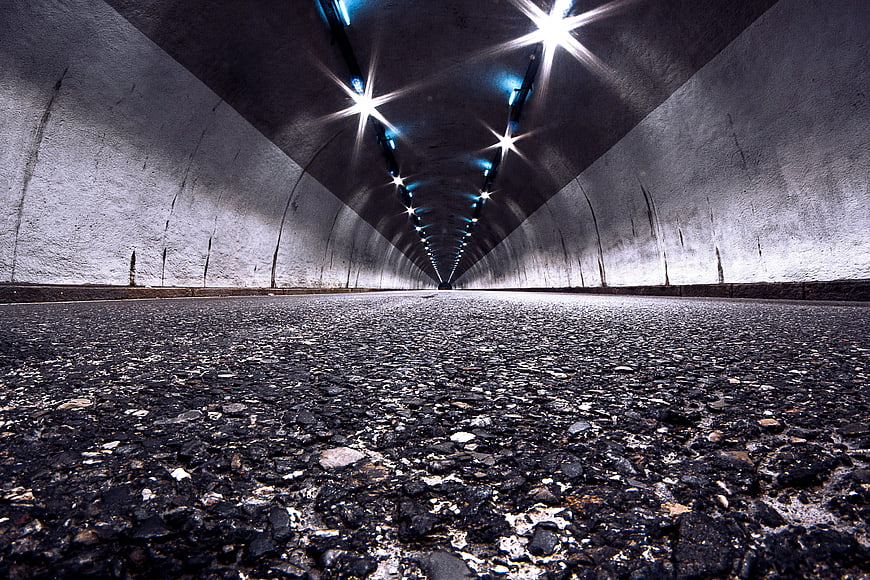 Low angle view of empty asphalt road inside concrete tunnel