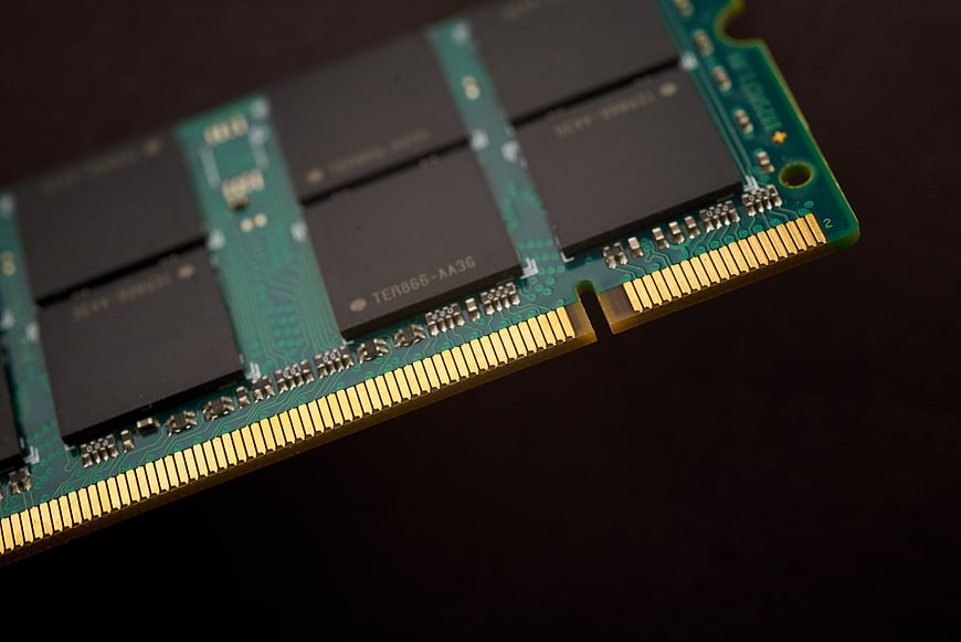 Close-up of green RAM stick with gold pins on dark background