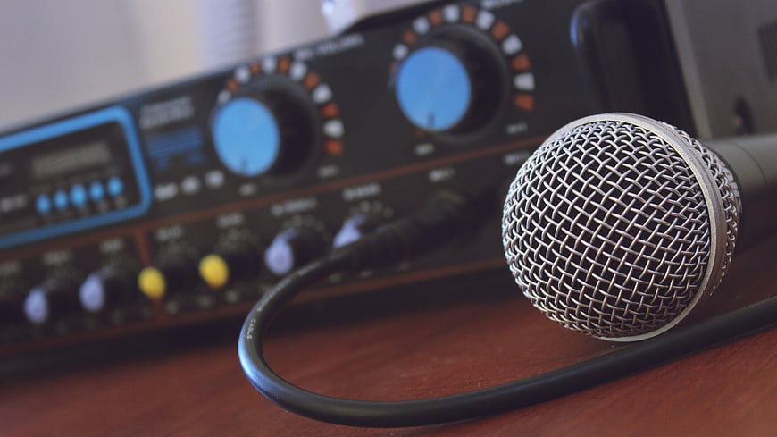 Close-up of Microphone and Audio Mixer on Wooden Desk