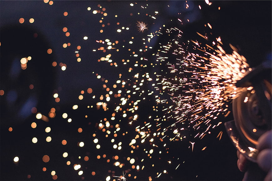 Angle grinder sparks flying in dark workshop