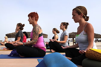Group of Women Meditating in Yoga Class on Beach