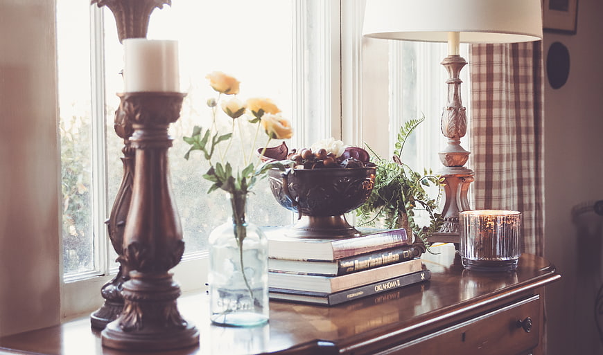 Rustic interior still life with books, flowers, and candle by window