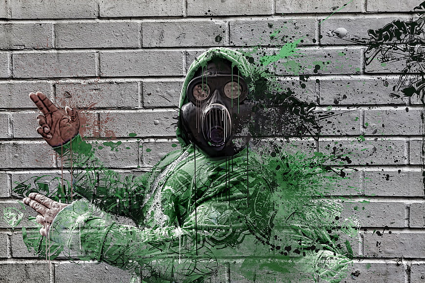 Graffiti of man in gas mask and green hoodie on brick wall
