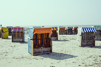 Colorful striped beach huts on sandy shore
