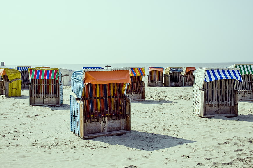 Colorful striped beach huts on sandy shore