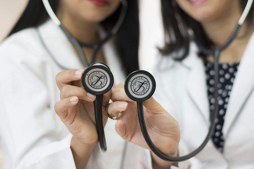 Two female doctors holding stethoscope chest pieces