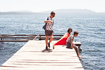 Friends playing beer pong on a wooden dock by the lake