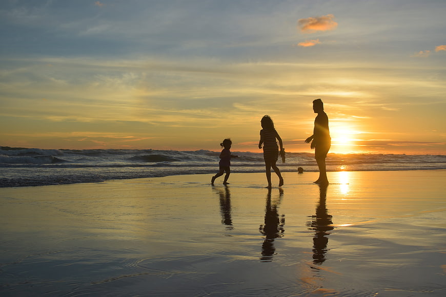 Family Silhouette Walking on Beach at Sunset
