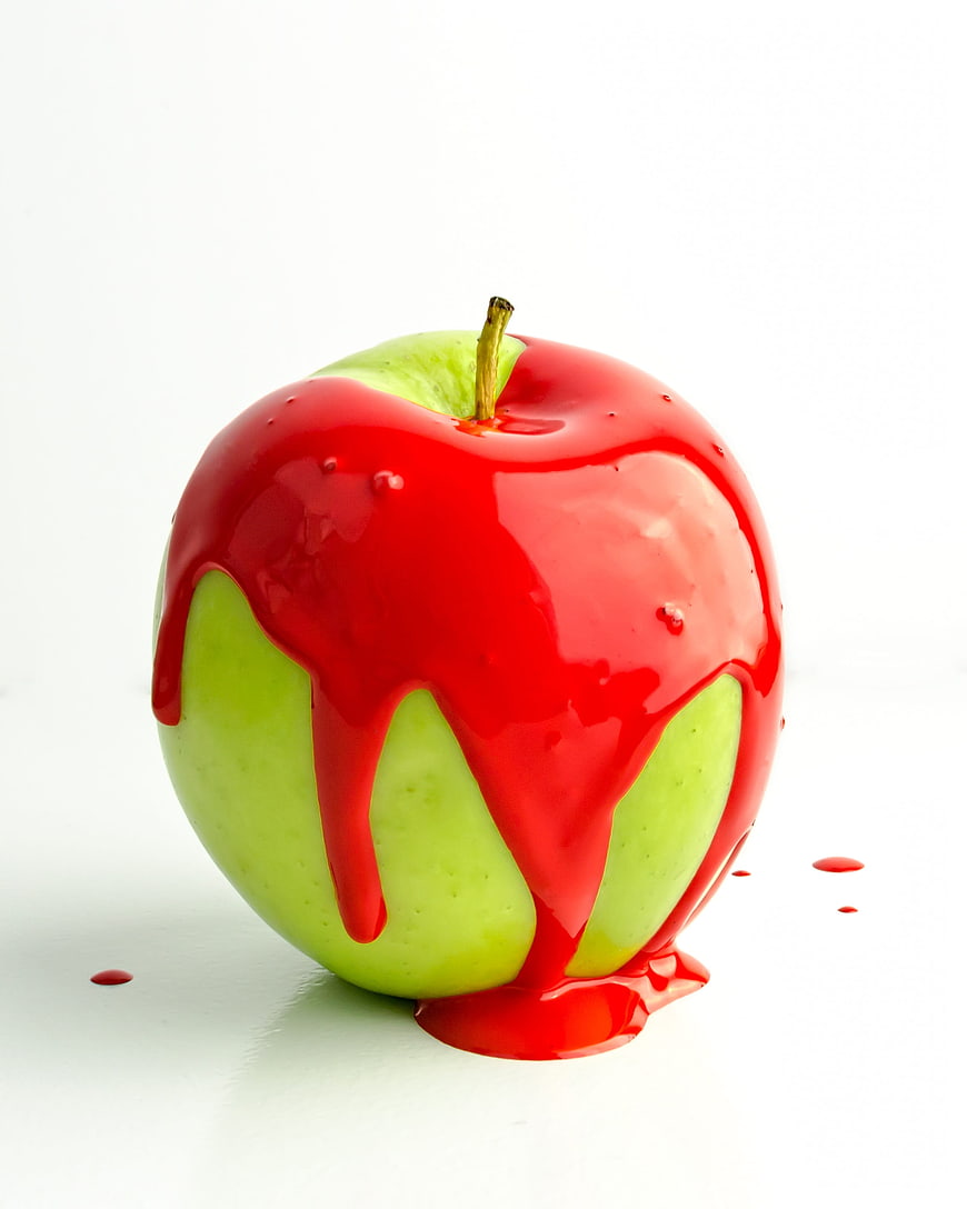 Green Apple Dripping with Red Glaze on White Background