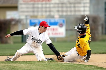Baseball player sliding into base while fielder attempts tag