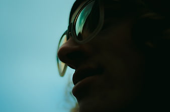 Close-up profile of man wearing glasses against blue sky