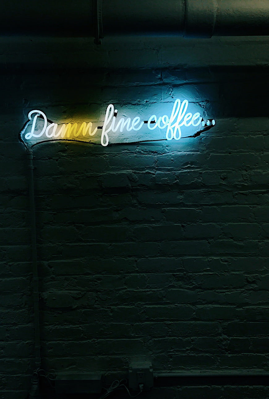 Neon Damn Fine Coffee Sign on Dark Brick Wall