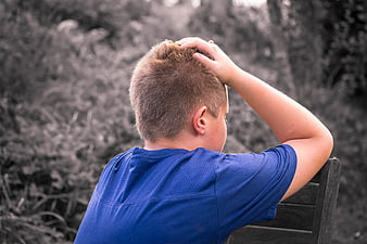 Sad Boy Sitting Alone on Bench with Hand on Head