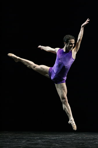 Male ballet dancer in purple leotard leaping mid-air