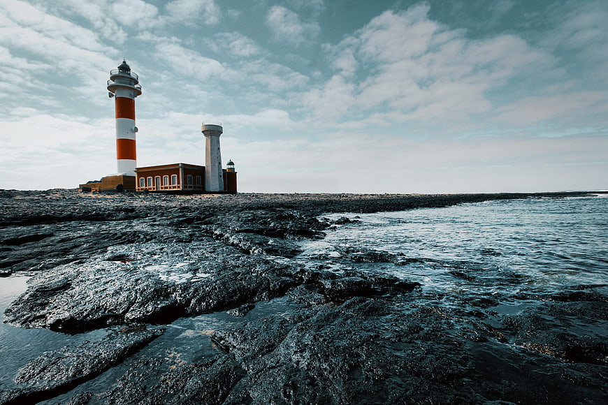 Lighthouse on Rocky Coastline with Blue Sky