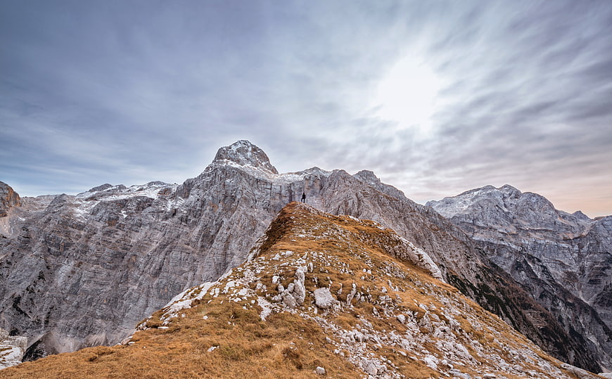 Lone Hiker on Alpine Ridge with Snowy Peaks