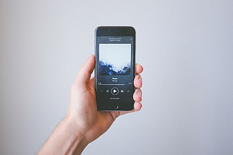 Hand holding smartphone playing music app on white background
