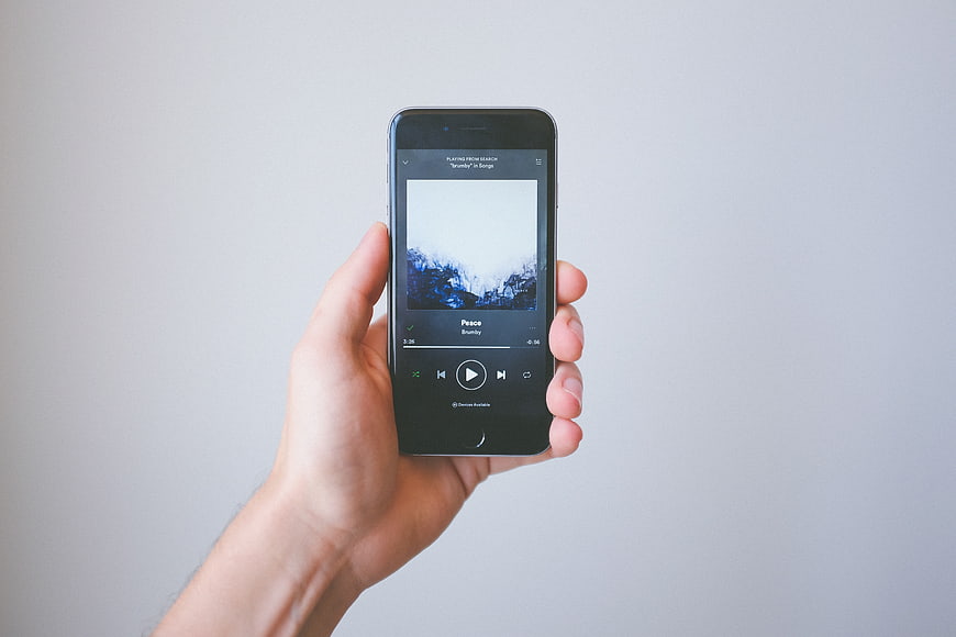 Hand holding smartphone playing music app on white background