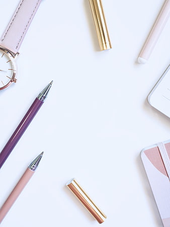 Minimalist feminine flat lay with pink and purple pens, watch, and notebook