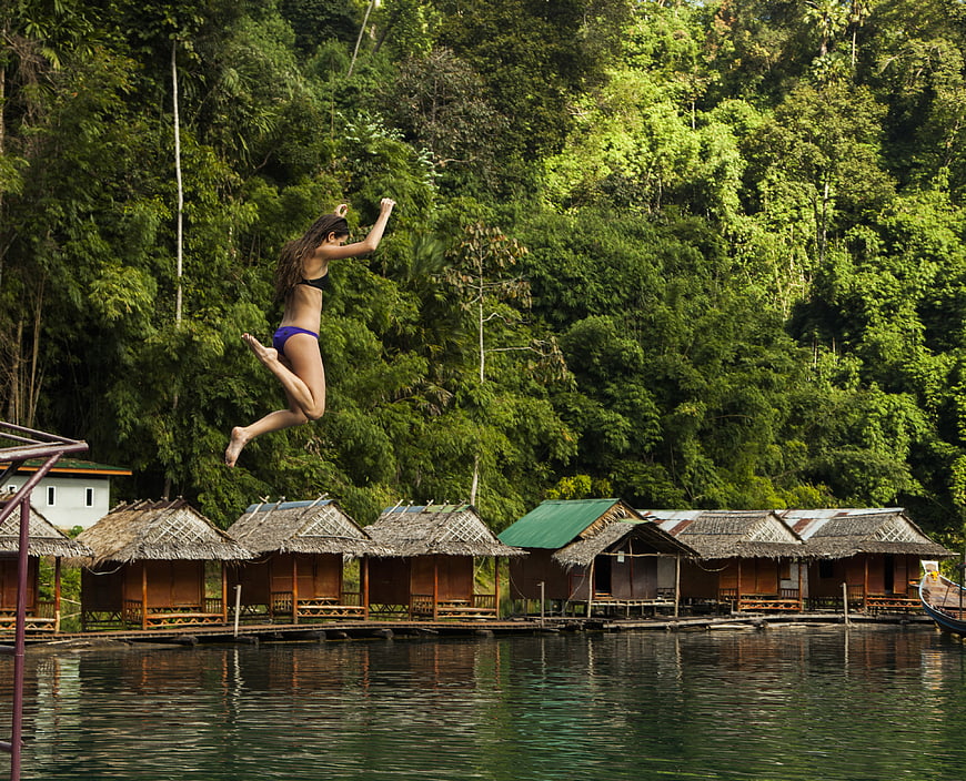 Woman Jumping into River Near Jungle Huts