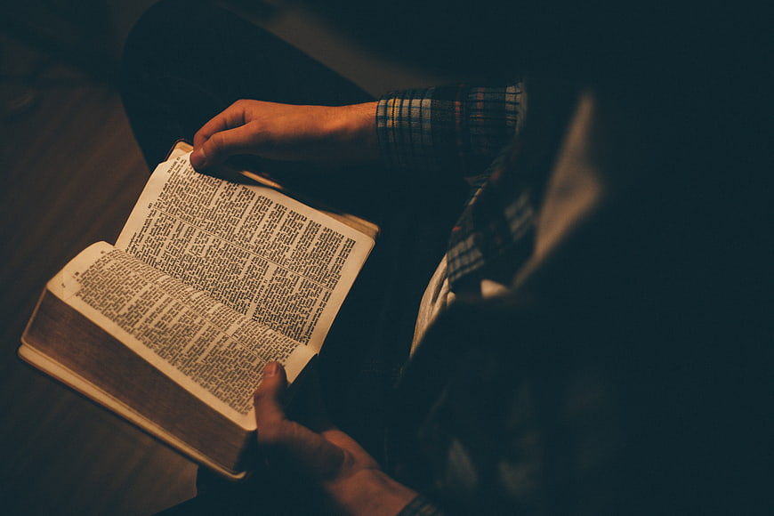 Man Reading Bible in Dark Room