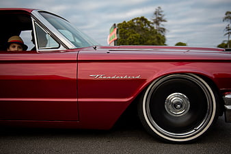 Side view of classic red Ford Thunderbird with child passenger