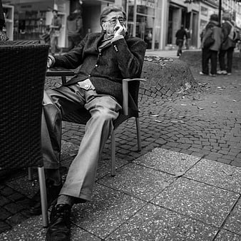 Senior man sitting at outdoor cafe in black and white