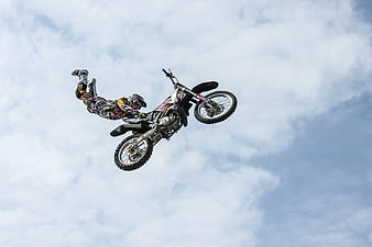Motocross Rider Performing Mid-Air Stunt Against Cloudy Sky