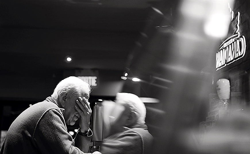 Senior man resting head in hand at dimly lit bar