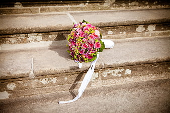 Pink and purple bridal bouquet on weathered stone steps